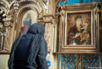 femeie rugându-se în fața icoanei Maicii Domnului