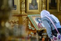 femeie închinându-se la icoana Mântuitorului Hristos