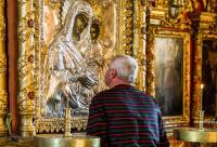 bărbat în fața icoanei Maicii Domnului