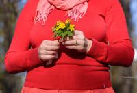 femeie în bluză roșie cu un buchet mic de flori galbene în mână