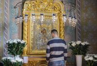bărbat în fața icoanei Maicii Domnului