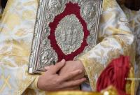 preot cu Sfânta Evanghelie în brațe