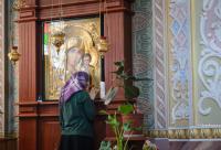 femeie în fața icoanei Maicii Domnului