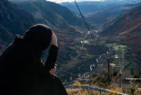 femeie cu batic privind de pe vârful muntelui