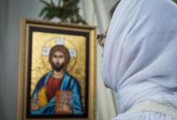 femeie în fața icoanei Mântuitorului Hristos