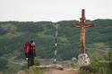 bărbat privind o cruce de lemn pe vârful muntelui