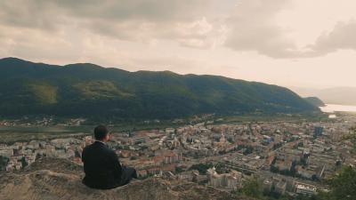 preot stând pe stâncă și privind orașul